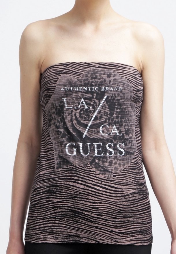 La personne porte un haut bustier avec des rayures zèbre et un grand motif floral indiquant "Authentic Brand L.A. / CA GUESS" sur le devant.