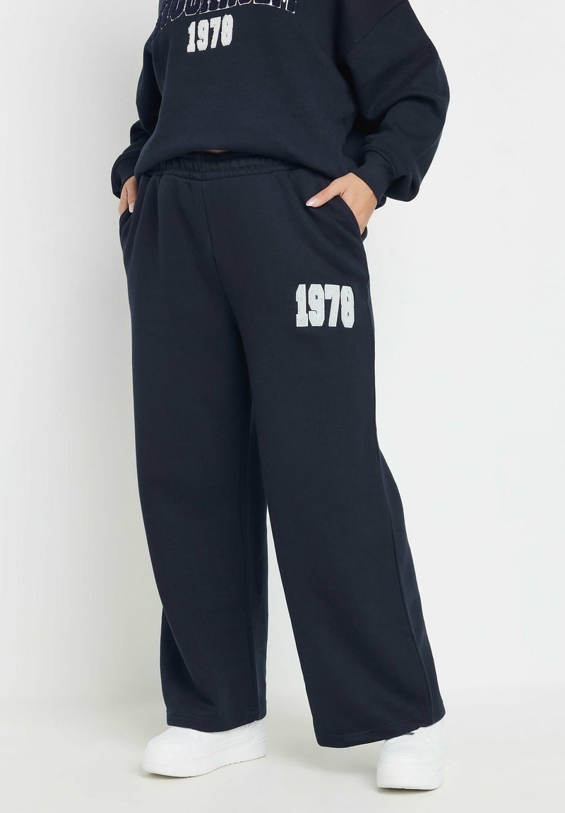 Marinblå sweatpants med elastisk midja, sidofickor och en djärv vit "1978" tryck på vänster ben. Mjukt tyg, avslappnad passform.