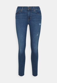 Vaqueros skinny azul oscuro con detalles desgastados, que presentan un diseño clásico de cinco bolsillos y presillas para cinturón, elaborados en material vaquero.