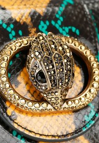 Chiusura in metallo dorato con ornamenti neri e dorati, su uno sfondo in pelle con motivo rettile verde e arancione.