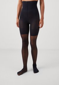 High-waisted black tights made of sheer material, featuring a smooth texture and opaque sections around the thighs. Subtle branding at the waistband.