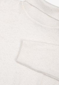 Weißer Pullover mit rundem Ausschnitt und engen Bündchen. Weiche Textur mit einem leichten Strickmuster und ohne sichtbare Marken oder Akzente.