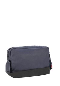 Borsa rettangolare in tela blu navy con base in tessuto nero, chiusura con zip e targhetta laterale. Caratterizzata da una superficie liscia e una costruzione robusta.