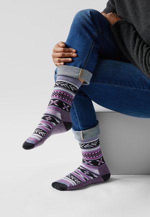 Calcetines estampados en colores morado, negro y gris con varios diseños. Material grueso con un puño acanalado y puntera y talón en contraste.