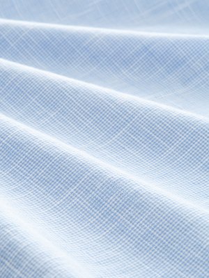 Světle modrá tkanina s tkanou mřížkovou strukturou. Textura je hladká s viditelnými záhyby, což naznačuje měkký a lehký materiál.
