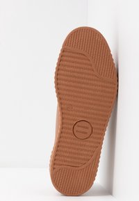 Semelle de chaussure marron avec un motif de grip texturé et un logo circulaire "SAMSOE SAMSOE" centré sur la semelle.