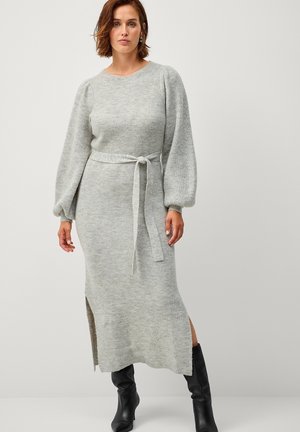 Abito lavorato a maglia grigio chiaro con maniche lunghe e voluminose, cintura legata in vita e spacco laterale. Tessuto morbido con motivo a coste. Stivali neri fino al ginocchio.