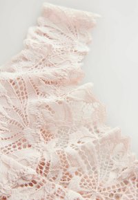 Delicate pink lace fabric featuring a scalloped edge and intricate floral patterns, showcasing fine texture and detailed openwork design.