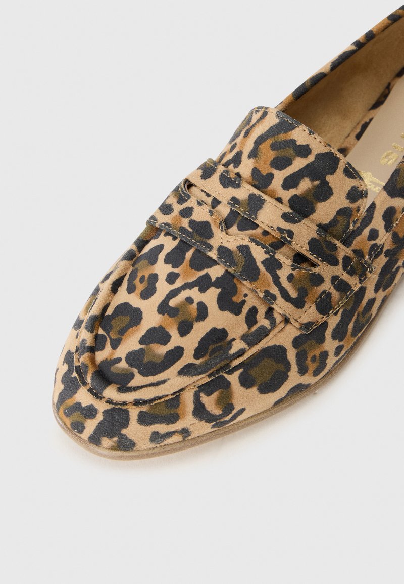 Mocassins pour femmes avec un imprimé léopard marron et noir et des détails en coutures sur l'avant, présentés sur un fond blanc.