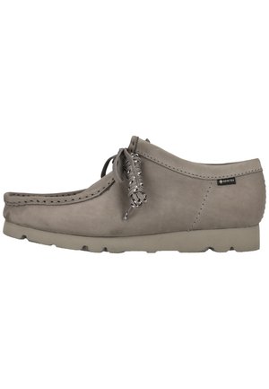 Lichtgrijze suède mocassin voor heren met dikke zool, veterstrik bovenop en Gore-Tex-label bij de hak.