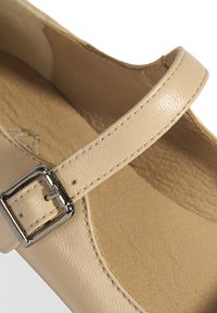 Beige Leder-Sandale mit strukturierter Oberfläche, ausgestattet mit einem schmalen Riemen und einer metallischen Schnalle sowie einer glatten Innenauskleidung.