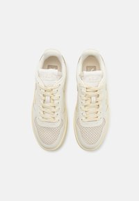 Sneakers in pelle crema con accenti perforati beige chiaro, punta rotonda e lacci beige. Nome del marchio "VEJA" impresso sulla linguetta.