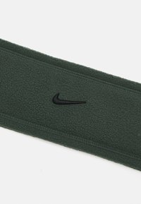 Tume roheline fliisist juukseside musta tikitud Nike logo ja õmmeldud servadega, millel on pehme tekstuur. Lihtne, lai disain mugavuse tagamiseks.