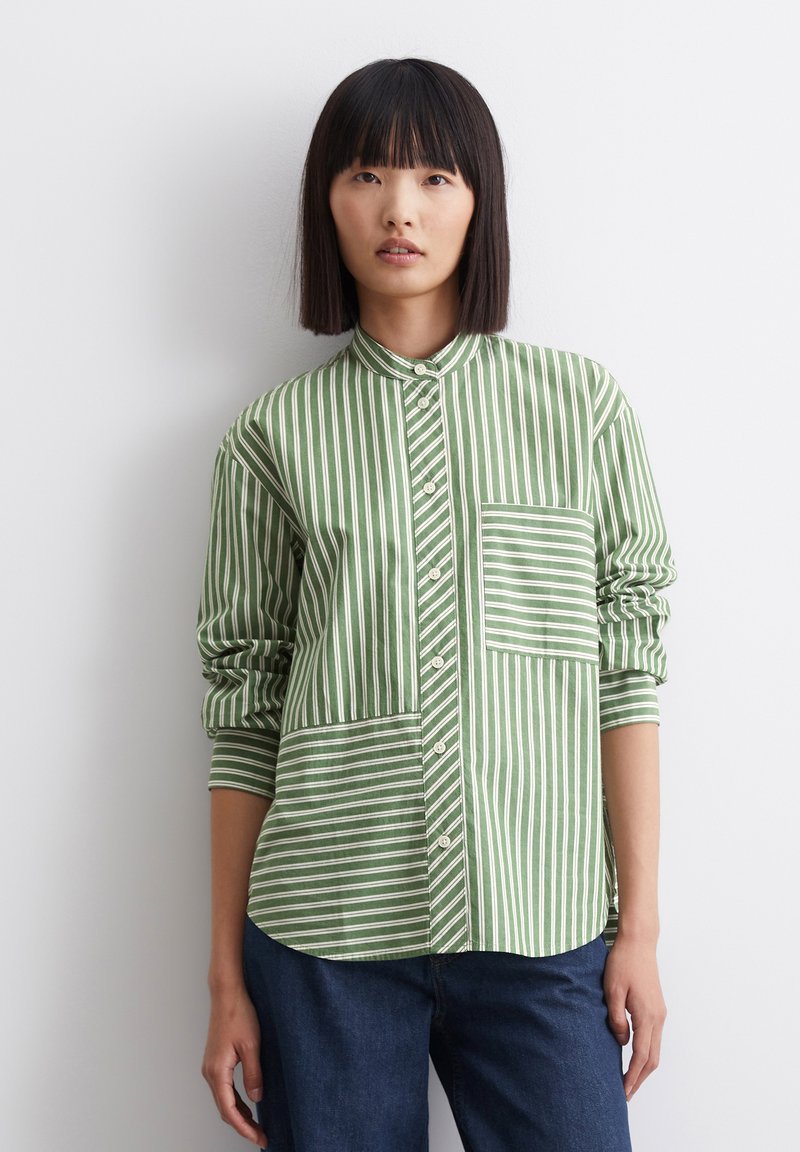 Chemise à boutons rayée verte et blanche avec col mandarin, poche poitrine et manches roulées. Fabriquée en tissu léger.