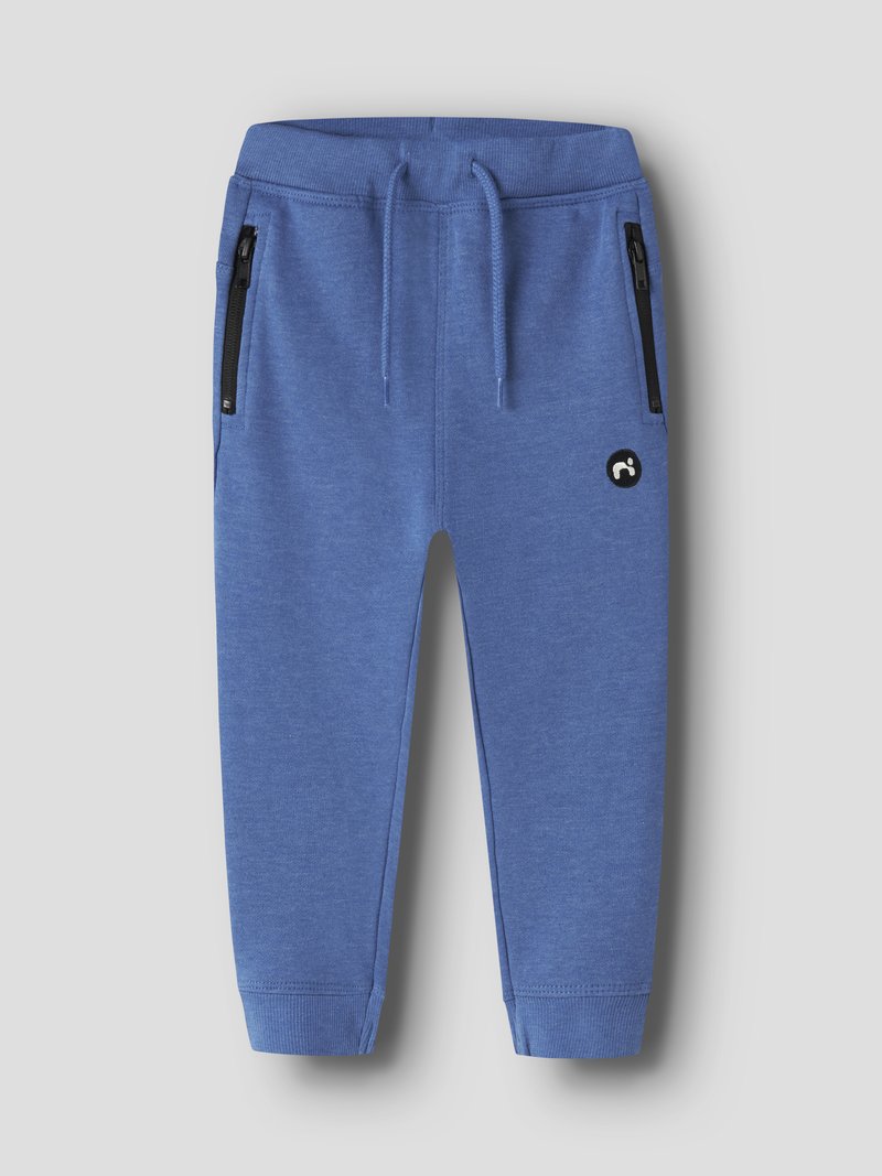Pantalon de jogging pour enfants bleu avec taille élastique, cordon de serrage, poches latérales zippées, poignets côtelés et petit logo circulaire noir sur la cuisse.