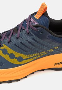 Running shoe with dark blue mesh upper, yellow accents, purple laces, and an orange heel tab. Textured sole for grip.