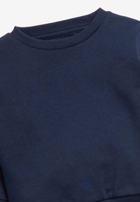 Felpa di un blu scuro con scollo rotondo a costine e tessuto texturizzato, con una finitura liscia e senza motivi o dettagli visibili.
