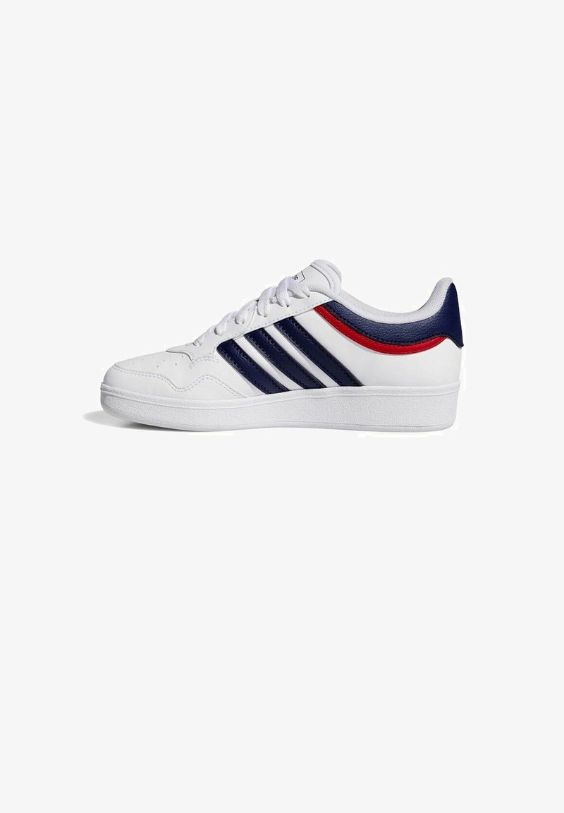 Zapato deportivo blanco con tres franjas azul marino, acento rojo, parte superior de cuero liso, suela de goma elevada, diseño con cordones y cuello acolchado.