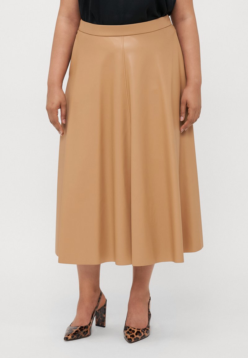 Kuningan midi skirt faux kulit dengan tekstur halus, bentuk A-line, dan pinggang lebar. Dipadukan dengan sepatu hak tinggi motif binatang dengan ujung runcing.