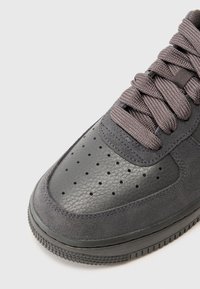 Grå sneaker i läder och mocka med strukturerad yta, perforerad tåbox och matchande snören. Gummisula.