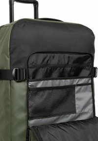 Borsa da viaggio a rotoli in tessuto verde e nero; presenta una grande tasca frontale, dettagli in rete e spallacci regolabili. Superficie testurizzata.