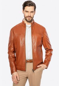 Giubbotto in pelle marrone con colletto alto, chiusura con zip, tasche laterali e dettagli cuciti. La texture liscia e il design aderente sono evidenti.