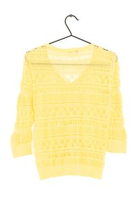 Un pull en tricot jaune avec un col en V, des manches trois-quarts et un motif de dentelle ajourée, suspendu à un crochet noir.