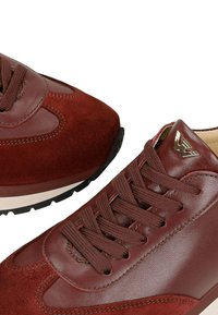 Baskets en cuir bordeaux et en suède avec des semelles texturées, des bouts ronds, des lacets assortis et un logo métallique sur la languette.
