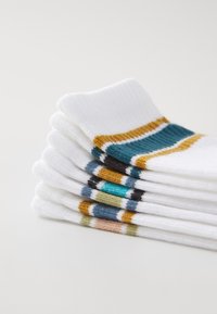 Calzini bianchi impilati con strisce multicolorate in blu, oro e nero. Realizzati in un tessuto morbido e testurizzato.