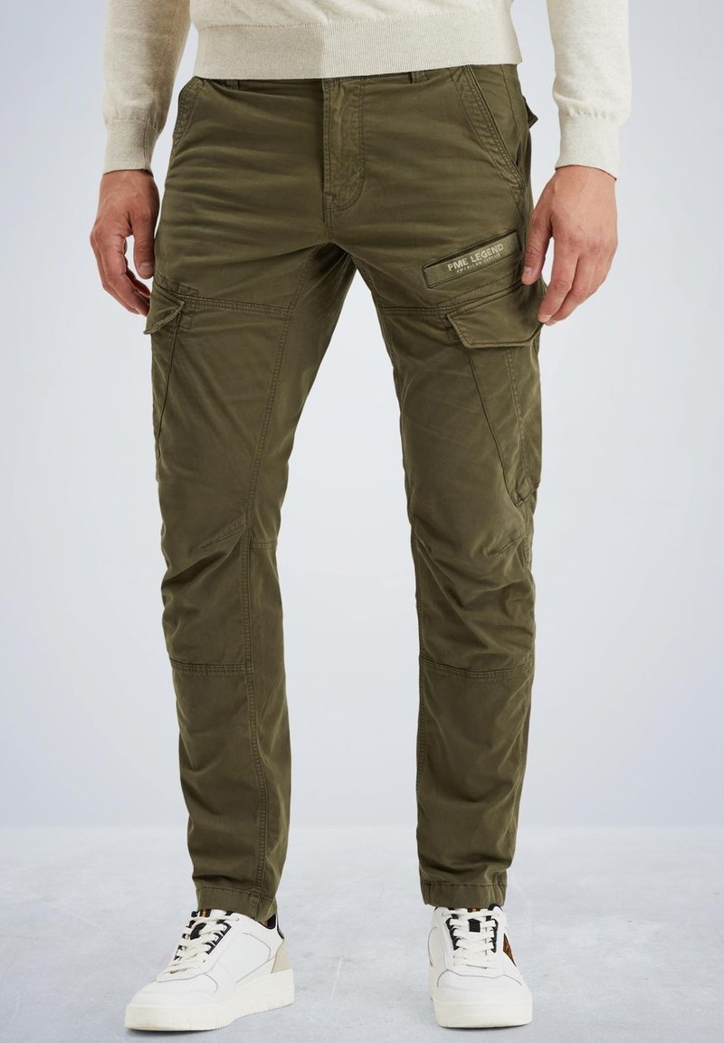 Olivenfarbene Cargo-Hosen mit mehreren Taschen, schmaler Schnitt, texturierten Stoff; kombiniert mit weißen Sneakers mit schwarzen und beigefarbenen Akzenten.