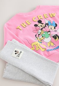Lyserød sweatshirt med teksten "THE CREW" og tegneseriefigurer, kombineret med grå ribstrikkede leggings med et Mickey Mouse-mærke.