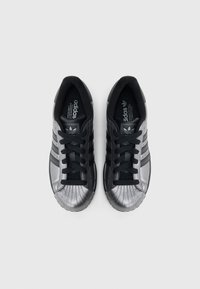 Μαύρα και μεταλλικό ασημί αθλητικά παπούτσια με τρεις μαύρες ρίγες, υφασμένο κάλυμμα δακτύλων, μαύρα κορδόνια και λεπτομέρειες λογότυπου στη γλώσσα.