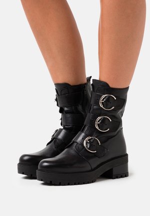 Botines de cuero negros con tres hebillas de plata, punta redonda, tacón grueso y acabado texturizado, con cremallera lateral para un fácil uso.