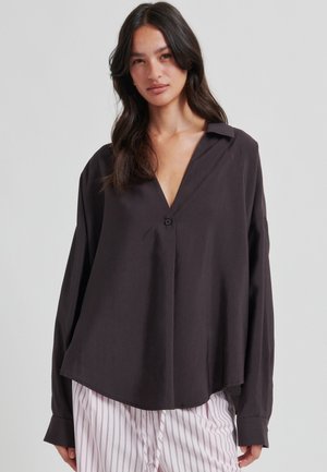 Rento, tummanharmaa paita, jossa V-aukko, pitkät hihat, yksittäinen napitus ja kaareva helma; valmistettu sileästä kankaasta.