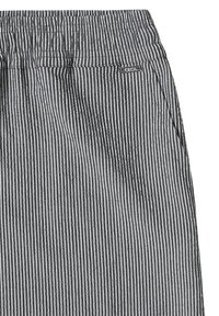 Pantalon en tissu rayé verticalement gris et blanc avec une taille élastique et une petite étiquette rectangulaire portant l'inscription « CECIL » près de la poche.
