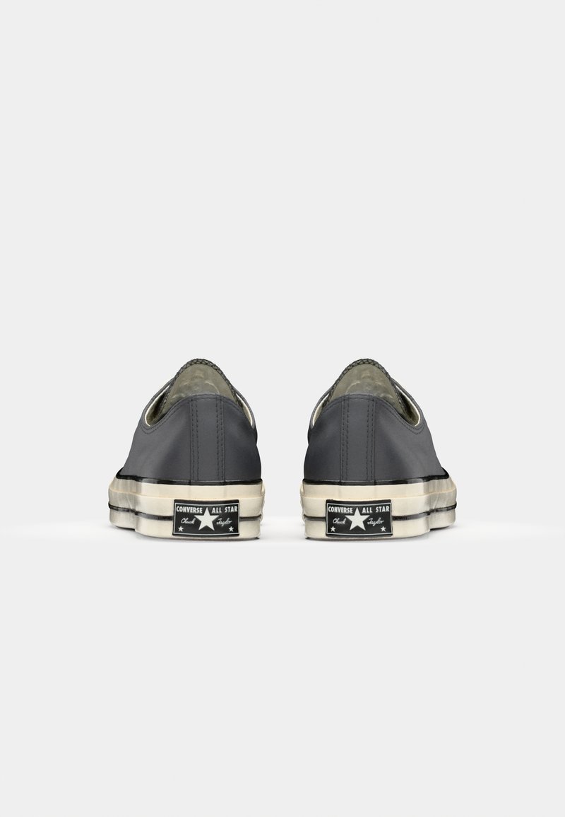 Grå canvas slip-on sneakers med rundede tæer, gummisåler og falmede hvide accenter. Funktionen inkluderer et sort logo mærke på hælen.