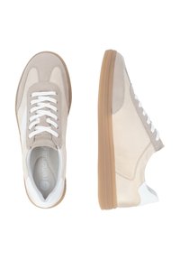 Beige suede sneakers with a white leather accent, featuring a rounded toe, white laces, and a light brown rubber sole.