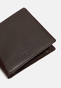 Brązowy skórzany portfel z wytłoczonym logo, gładką teksturą, kwadratowym kształtem i starannym przeszyciem wzdłuż brzegów.