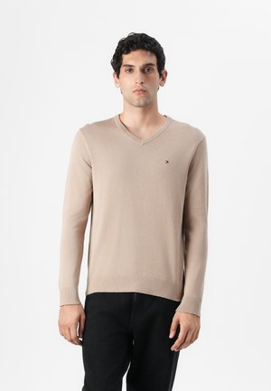 Beige Strickpullover mit V-Ausschnitt und langen Ärmeln, ausgestattet mit einem kleinen Logo auf der Brust sowie gerippten Bündchen und Saum.