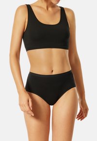 Svart tvådelat set med en ärmlös crop top med rundad halsringning och högmidjade shorts. Slät tyg med matt finish.