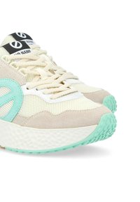 Sport sneakers met een bovenwerk van gaas en beige suède accenten, met een teal logo, witte tussenzool en een gestructureerde rubberen buitenzool.