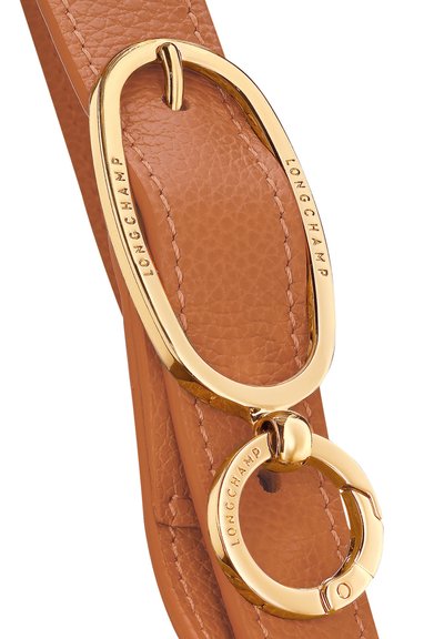 Hellbrauner Lederriemen mit glatter Textur, ausgestattet mit einer glänzenden goldenen ovalen Schnalle und einem kreisförmigen Ring, die beide mit "LONGCHAMP" geprägt sind.