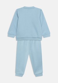 Σετ για νήπιο σε φωτεινό γαλάζιο χρώμα, δύο τεμαχίων με μακρυμάνικη μπλούζα και παντελόνι, κατασκευασμένο από μαλακό ύφασμα με ρεβέρ στα μανίκια και στους αστραγάλους.