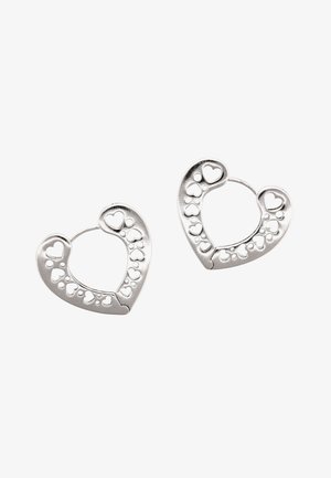 Sølv hjerteformede hoopsøreringe med flere små hjerteudskæringer langs kanterne på en hvid baggrund.
