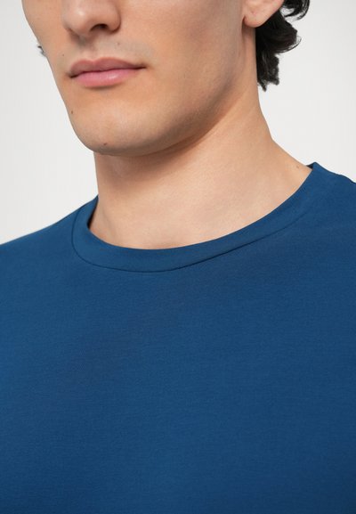 Modré bavlnené tričko s rebrovaným okrúhlym výstrihom, hladkou štruktúrou a priliehavým strihom, s minimom švov a jednofarebné.