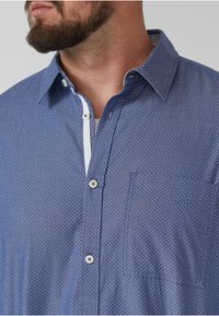 Koszula z krótkim rękawem w granatowym kolorze, zapinana na guziki, w białe kropki, z kieszonką, kontrastowym białym wykończeniem przy guzikach i klasycznym kołnierzykiem.