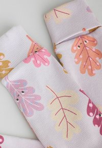Ribbad pastelllila strumpor med bladdesigner i rosa, gult och orange, med lekfulla detaljer och påtagliga texturer.