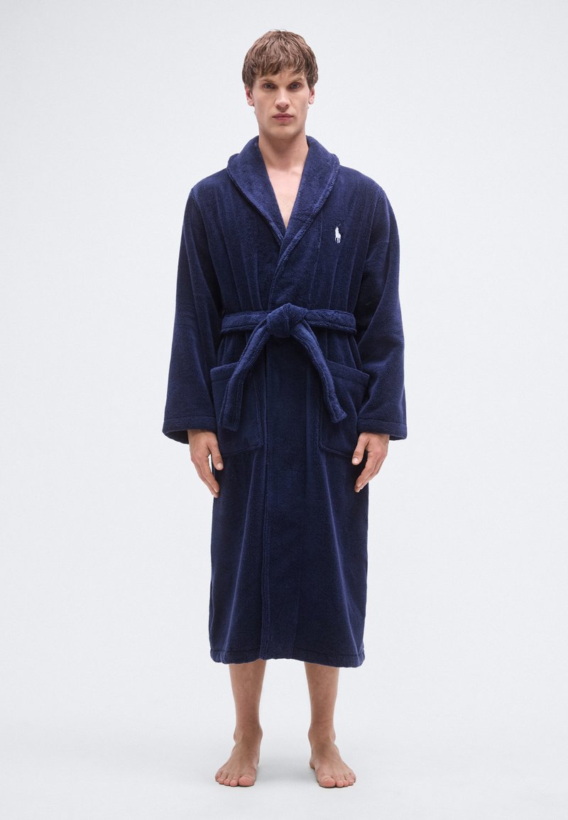 Marineblå badekåpe laget av mykt frottémateriale, med sjalkrage, midjebånd og to frontlommer. Liten logo på brystet.