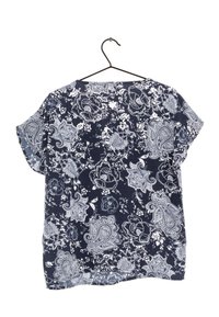 Marineblaues Shirt mit weißen Blumen- und Paisleymustern, kurzen Ärmeln und einem lässigen Schnitt. Das Material wirkt leicht und hat eine weiche Textur.