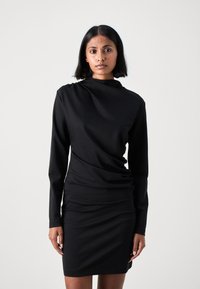 Černé šaty s dlouhým rukávem a volným střihem, vyrobené z hladké látky; slim fit, délka do poloviny stehna, s vysokým výstřihem a jemnou texturou.
